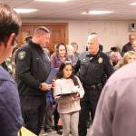 The Feb. 24 Enumclaw City Council was packed with residents, who gave Commander Tony Ryan, left, and Yosedely Barragan, center, a standing ovation for their actions, which saved the life of Yosedelys younger brother. Also pictured is Enumclaw Police Chief Bob Huebler / El Ayuntamiento de Enumclaw del 24 de febrero estaba lleno de residentes, quienes le dieron al Comandante Tony Ryan, a la izquierda, y a Yosedely Barragán, en el centro, una gran ovación por sus acciones, las cuales salvaron la vida del hermano menor de Yosedely. También se muestra en la foto el Jefe de Policía de Enumclaw Bob Huebler. Photo by Ray Miller-Still