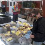 Everything you see on these tables have already been ordered, bought, and paid for by customers of the Enumclaw REKO Market, so all they have to do is drive up to the local Fantello Creamery to pick up their order. Pictured is REKO Market organizer Julie Kintzi in the flower mask and Steve Neason from Cedar Springs Farm, who was standing in for Cascadia Greens. Photo by Ray Miller-Still