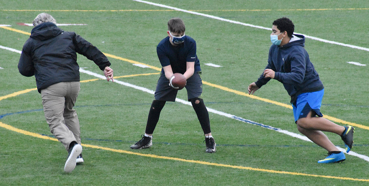 White River football players were running through drills last week, with masks in place and players spread throughout the practice field. Here, coach Jesse Reeves leads the way while Jayden Sams hands off to Ossyan Williams. Football practice for real is set to begin Feb. 10. Photo by Kevin Hanson