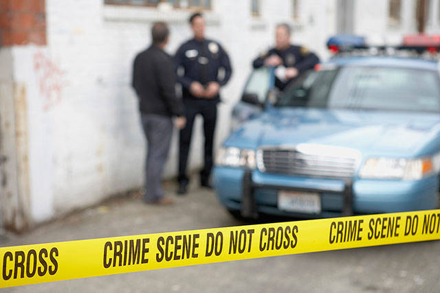 Male police officers standing behind Do Not Cross tape
