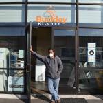 Teago Manoharan on March 16 holds open the door to the Buckley Kitchen, a commissary kitchen he started in 2019 that hosts a number of bakers and chefs who couldn't otherwise afford a space to cook. Photo by Alex Bruell