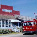 Walt Olsen climbs a ladder to remove the Daves Antiques sign from Buckley Hall. The fire equipment was provided by Joe Kolisch, a former Enumclaw fire chief. Photo courtesy the Foothills Historical Society
