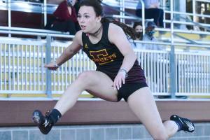 Sunny skies greet track and field athletes at Arrow Lumber Stadium Thursday afternoon. Enumclaw High made the trek across the river to take on their Buckley hosts, but headed home on the short end of the scoring. Here, Enumclaw's Ellie DeGroot clears a hurdle on the way to victory; also, a trio of White River runners complete a first lap on the track. Photo by Kevin Hanson