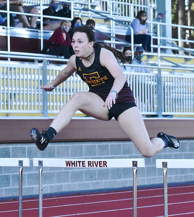 Sunny skies greet track and field athletes at Arrow Lumber Stadium Thursday afternoon. Enumclaw High made the trek across the river to take on their Buckley hosts, but headed home on the short end of the scoring. Here, Enumclaws Ellie DeGroot clears a hurdle on the way to victory; also, a trio of White River runners complete a first lap on the track. Photo by Kevin Hanson