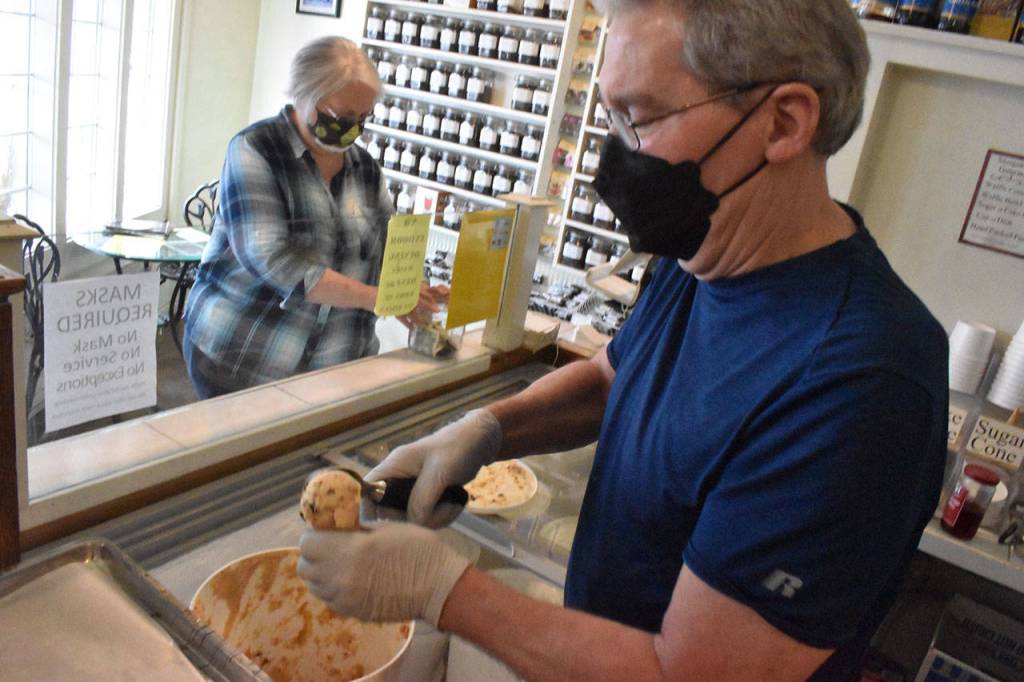 Toby Wenham scoops a cone of ice cream while his wife Peggy inspects the tip jar at Sweet Necessities. Photo by Alex Bruell