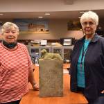 JoAnn Taylor, left, and Winona Jacobsen, right, pose for a picture at the Bonney Lake Public Works Center flanking the gravemarker of former Lake Tapps area Daisey Kirtley, who died in 1886 at the age of eight. This year, her gravemarker is being reunited with her family at the Buckley Cemetery.