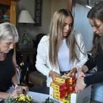 From left to right: Julie Reece-DeMarco and her daughters Natalie and Sophia DeMarco organize and pack supplies for Afghan families coming to the Pacific Northwest area.