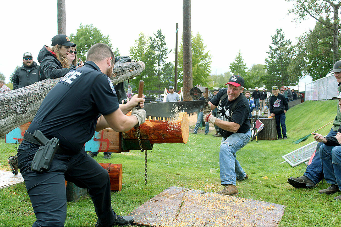 Local police officer Arthur Fetter competes with his father, Jeff, in the Double Bucking event. Photo by Ray Miller-Still.