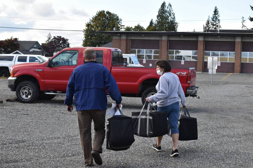 Volunteers load hot meals for seniors in the Enumclaw Senior Center parking lot. Photo by Alex Bruell