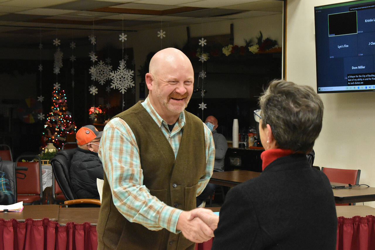 Beau Burkett and Pat Johnson shake hands after concluding the oath of office. Photo by Alex Bruell