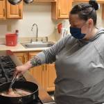 Volunteer Annie Davisson, frying bacon over the Senior Centers kitchen stovetop, helps prepare the BLT sandwiches to be delivered to seniors the morning of March 3. Photo by Alex Bruell