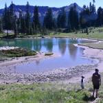 Hiking the Naches Peak Loop Trail begins and ends with the iconic view of Tipsoo Lake with Mount Rainier in the background. This photo shows a family enjoying a stop at a small alpine pond. Photo by Kevin Hanson