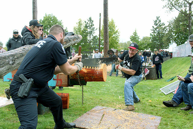 Local police officer Arthur Fetter competes with his father, Jeff, in the Double Bucking event last year. Photo by Ray Miller-Still