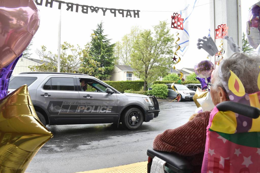 An Enumclaw Police Officer waves to Elma on her 106th birthday. Police and firefighters stopped by the assisted living community she lives at to wish her a happy birthday May 26, although the firefighters had to leave early to respond to a call for service. Photo by Alex Bruell