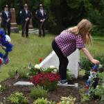 `Photo by Alex Bruell
Mila Finn (left), 4, and Aria Finn, 6, place wreaths at the base of the new Never Forget Garden.