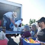 Jay Hill (cowboy hat) and Bill Petersen, warehouse supervisors at the Sumner Food Bank, unload food for families on July 13 in the parking lot of the Buckley Eagles hall atop their truck from the Sumner Food Bank. Photo by Alex Bruell.