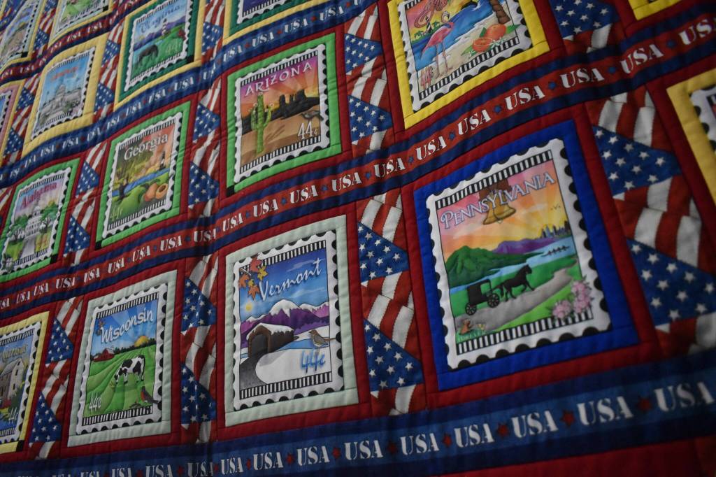Lisa Larkins A Marathoners Story quilt, containing postcard designs from each of the 50 states and several other landmarks, made to commemorate her husbands marathons in each of those locations.
