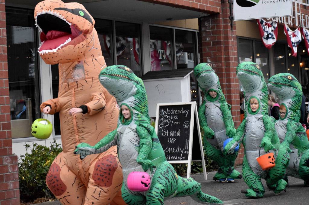 A fearsome Tyrannosaurus Rex leads what appears to be a herd of Velociraptors on a hunt for sweets. Not pictured but just out of frame are their handlers wearing Jurassic Park themed gear. Photo by Alex Bruell.
