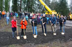 Foothills Rails to Trails Executive Director Shayla Miles, former Buckley Mayor Pat Johnson, former Enumclaw Mayor Liz Reynolds, King County Executive Dow Constantine, Pierce County Executive Bruce Dammeier, and King County Parks and Rec Director Warren Jimenez pose with their ceremonial shovels in front of the crowd gathered at the groundbreaking. Photo by Ray Miller-Still