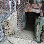 Leading down to the locker rooms is a dark stairwell, where athletes and coaches sometimes find sleeping bags, needles, and other detritis left by unhoused people. Photo by Ray Miller-Still