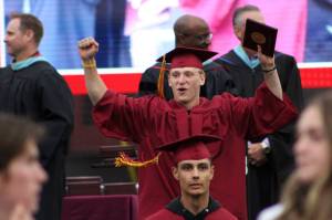 A student celebrates receiving his diploma.