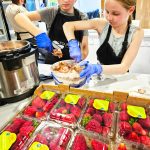 Molly Dacey and Addy Wooldridge scoop some Neapolitan ice cream into small bowls for people attending the Full Bellies free meal event on Thursdays. Photo by Ray Miller-Still