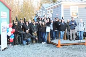 Photos by Ray Miller-Still
Volunteers and employees with Operation Tiny Home, Building Beyond the Walls, the Roots Collective, and other organizations celebrating Mike Lanes new home, which was still receiving finishing touches as speeches were given.
