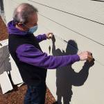 Construction expert Will Martin taking some measurement of the siding of a house in Enumclaw's Suntop Farms. Photo by Ray Miller-Still