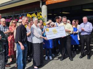 A $20,000 check was given from QFC staff to Plateau Outreach Ministries Executive Director Elisha Smith-Marshall (holding the left end of the check) on June 6. Photo by Ray Miller-Still