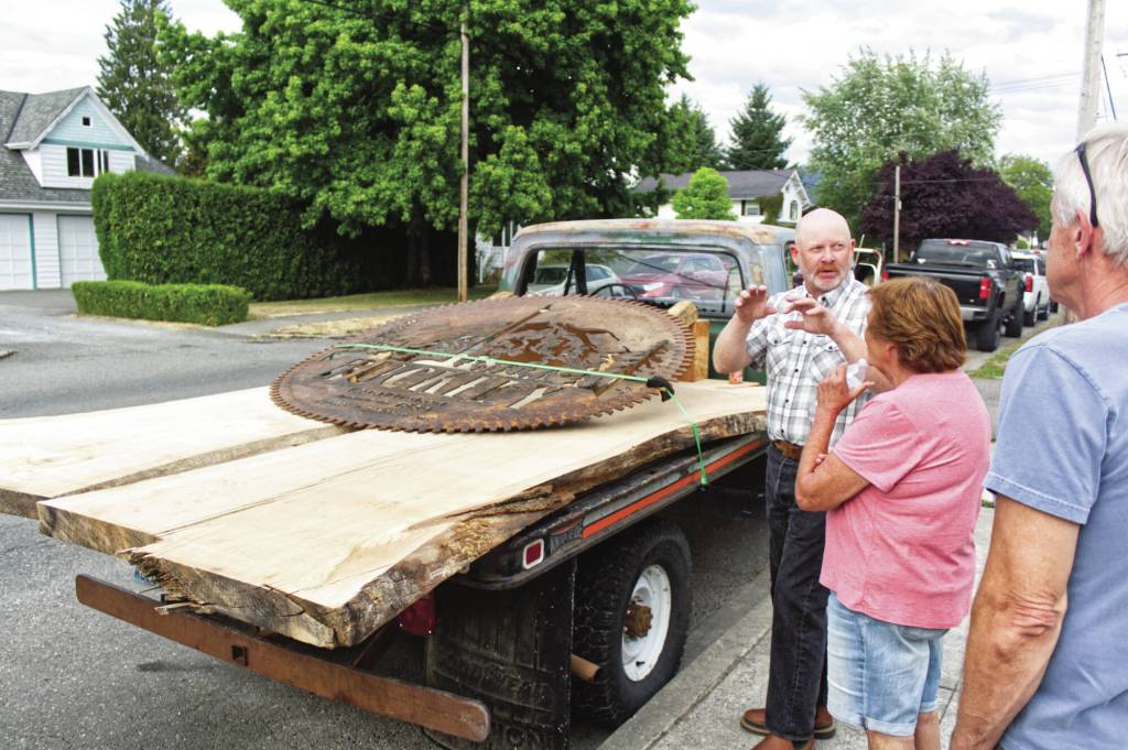 Photo by Ray Miller-Still
Mayor Beau Burkett showing off the metal saw artwork that will soon be on display outside city hall, as well as the wood of a tree that had to be cut down for construction. Instead of throwing it away, it will be turned into a conference table.