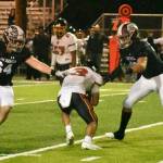 Thomas Jefferson quarterback Mabin Guillen is in deep trouble, about to be sacked by Hornets Nik Storem (64) and Kannius Thomson (99).