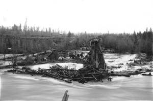 Photo by Karl Jensen / courtesy Enumclaw Plateau Historical Museum
To the left of this photo, which faces Enumclaw, is the first White River Bridge, part of the planned Naches to Yakima highway. That bridge was first built in 1897, then lost in a 1908 flood. Two houses are visible between the flooded road and the railroad trestle. Boise Creek can be faintly seen between the two bridges, where it drops 70 feet from the Enumclaw Plateau to the White River channel.