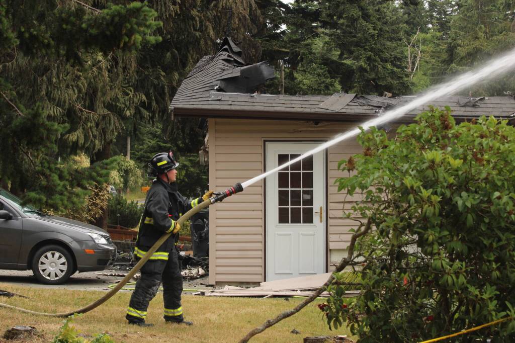 Photo by Allyson Ballard. A firefighter from Central Whidbey Island Fire and Rescue sprayed the neighboring home.